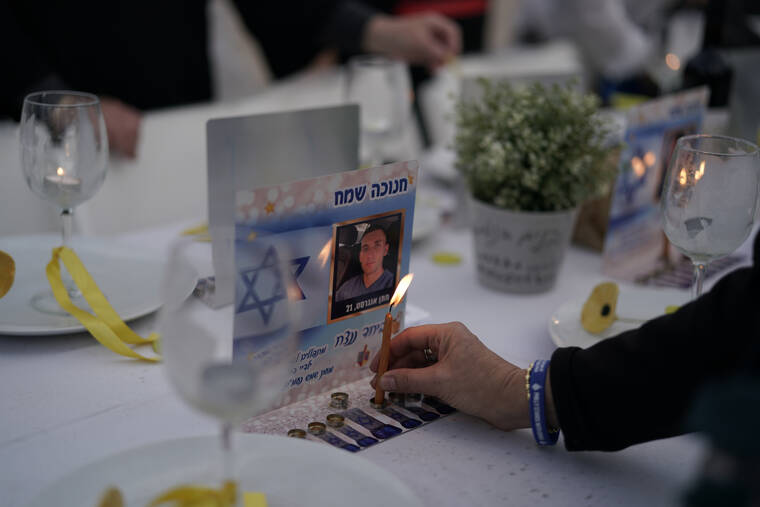 LEO CORREA / AP
                                A person lights a candle on a table set for hostages being held in the Gaza Strip by the Hamas militant group during the Jewish holiday of Hanukkah in the Hostages Square at the Museum of Art, in Tel Aviv, Israel, Friday, Dec. 8.