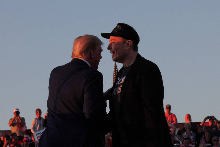 REUTERS/BRIAN SNYDER
                                Tesla CEO and X owner Elon Musk stands with Republican presidential candidate former President Donald Trump during a campaign rally in Butler, Penn.