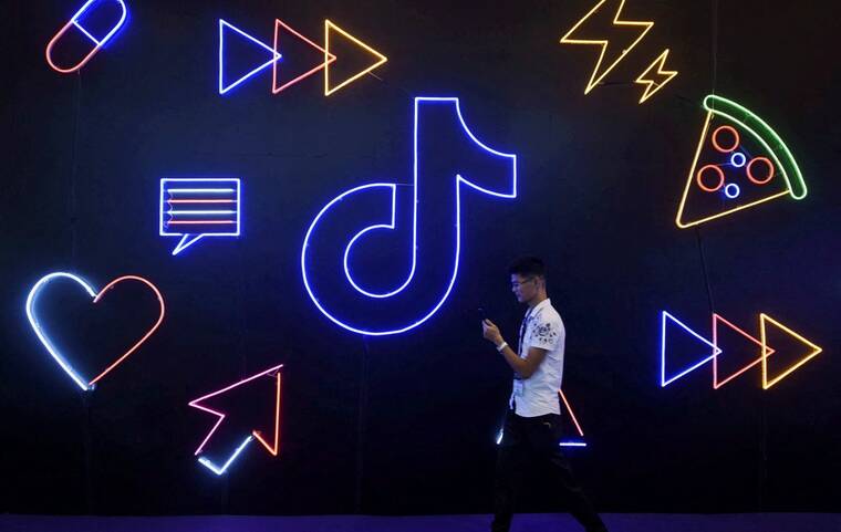 REUTERS/STRINGER/FILE PHOTO
                                A man holding a phone walks past a sign of Chinese company ByteDance’s app TikTok, known locally as Douyin, at the International Artificial Products Expo in Hangzhou, Zhejiang province, China, in October 2019.